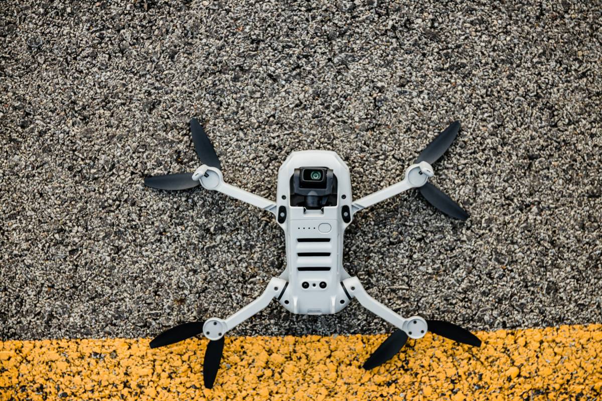 A small DJI drone with its arms unfolded, resting on tarmac beside a yellow line