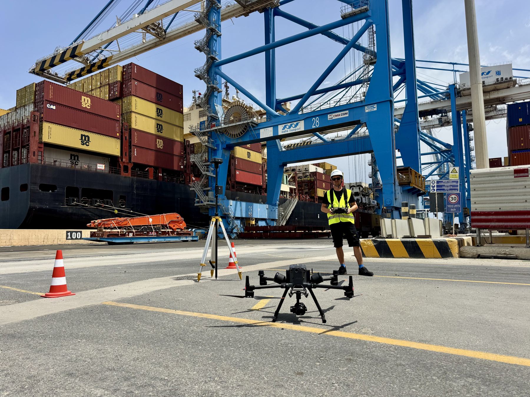 A DJI Matrice drone ready for take-off at Malta Freeport, its pilot holding the controller behind it