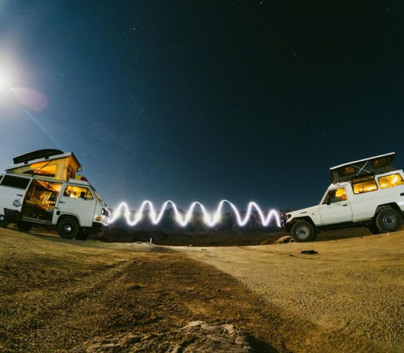 Two camper vans at night, a spiral of light painted between them under the stars
